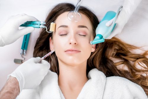 Beautiful woman with cosmetology tools lying on the medical couch. Facial treatment concept