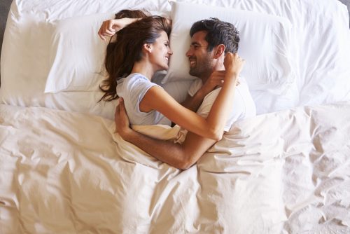 Overhead View Of Romantic Couple Lying In Bed Together